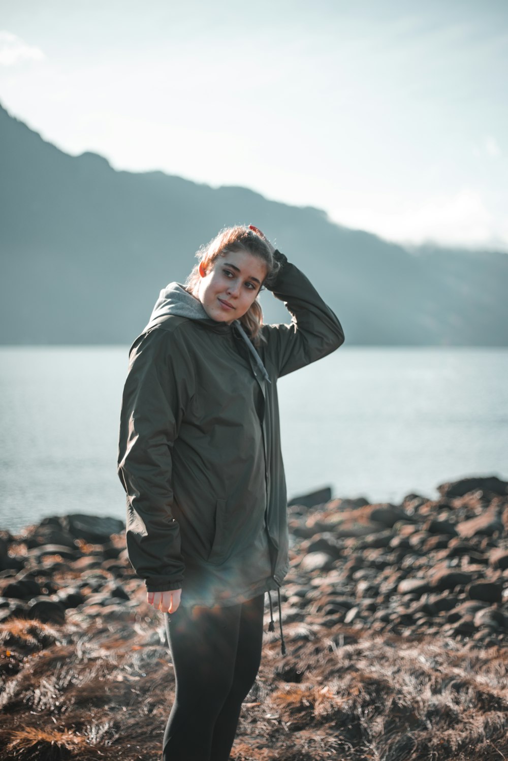 man in black jacket standing on rocky shore during daytime