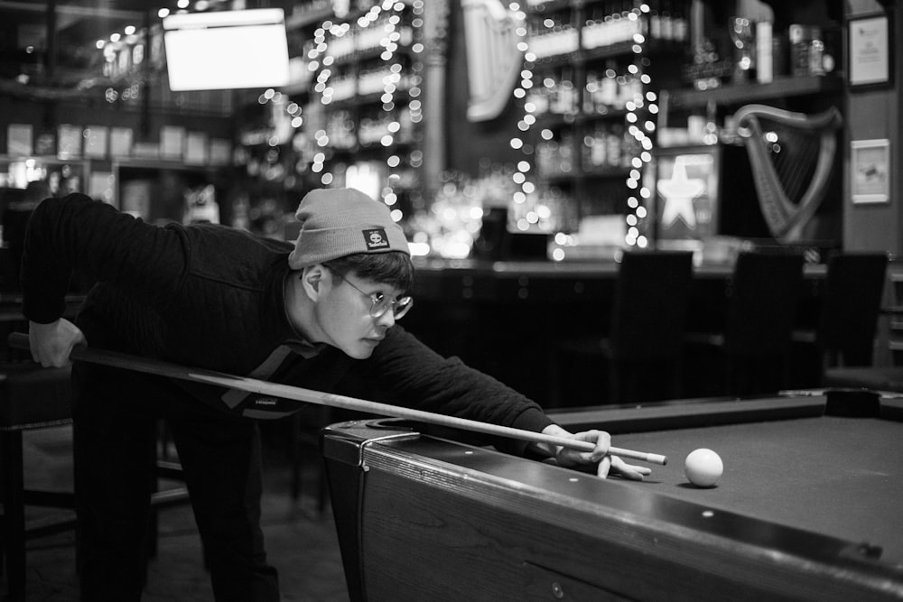 grayscale photo of man playing billiard