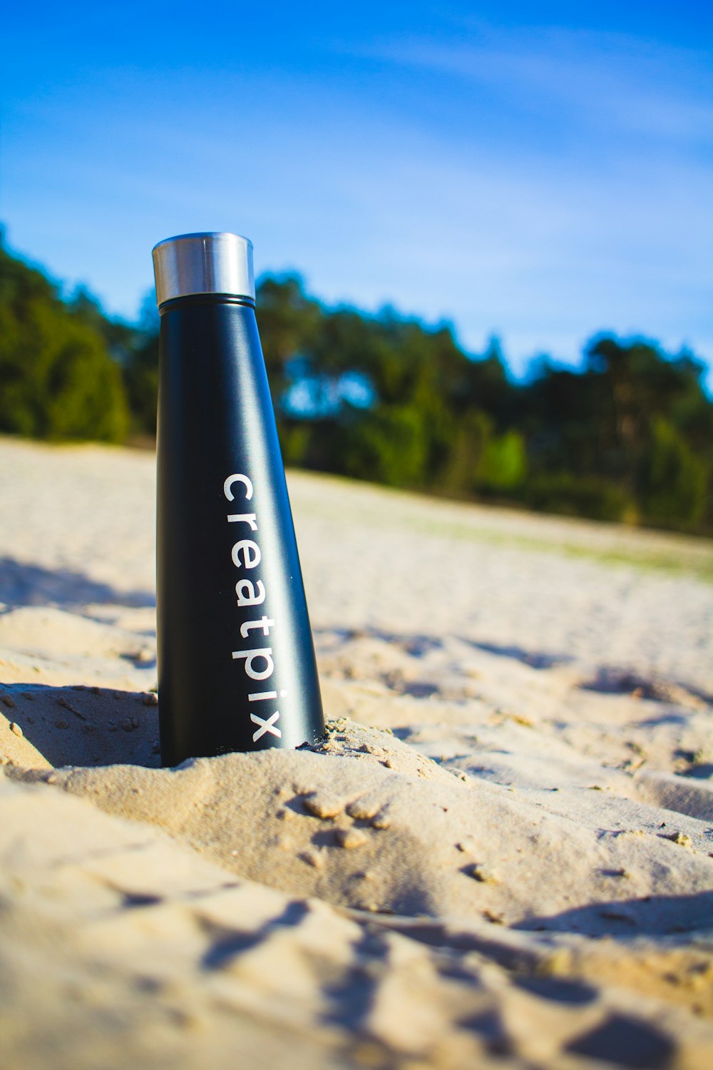 black and white calvin klein bottle on brown sand during daytime