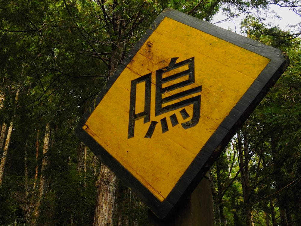 a yellow and black sign in a forest