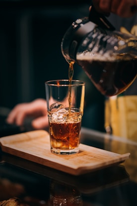 clear drinking glass with brown liquid on brown wooden table