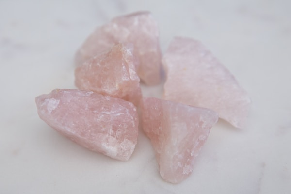 Smooth rose quartz hearts arranged delicately on a wooden surface.