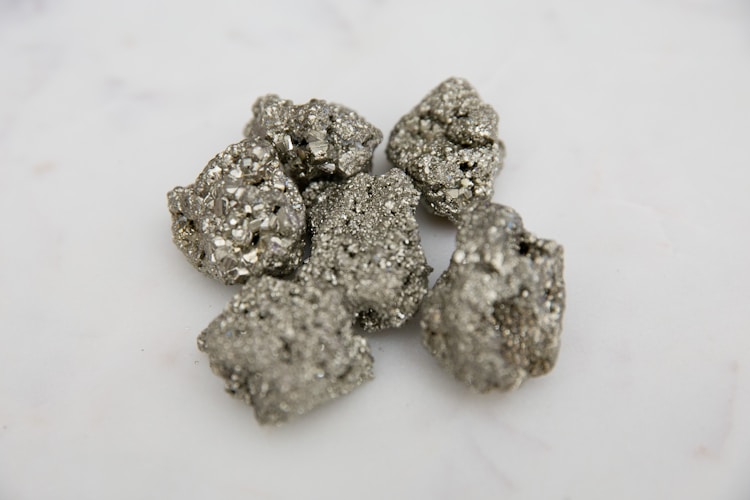 A stone fragment showing natural mineral composition, representing the raw geological material from which gold must be extracted