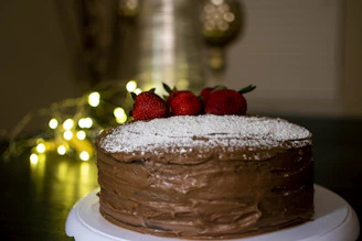 An overhead shot of a chocolate cake topped with fresh berries and a light dusting of powdered sugar