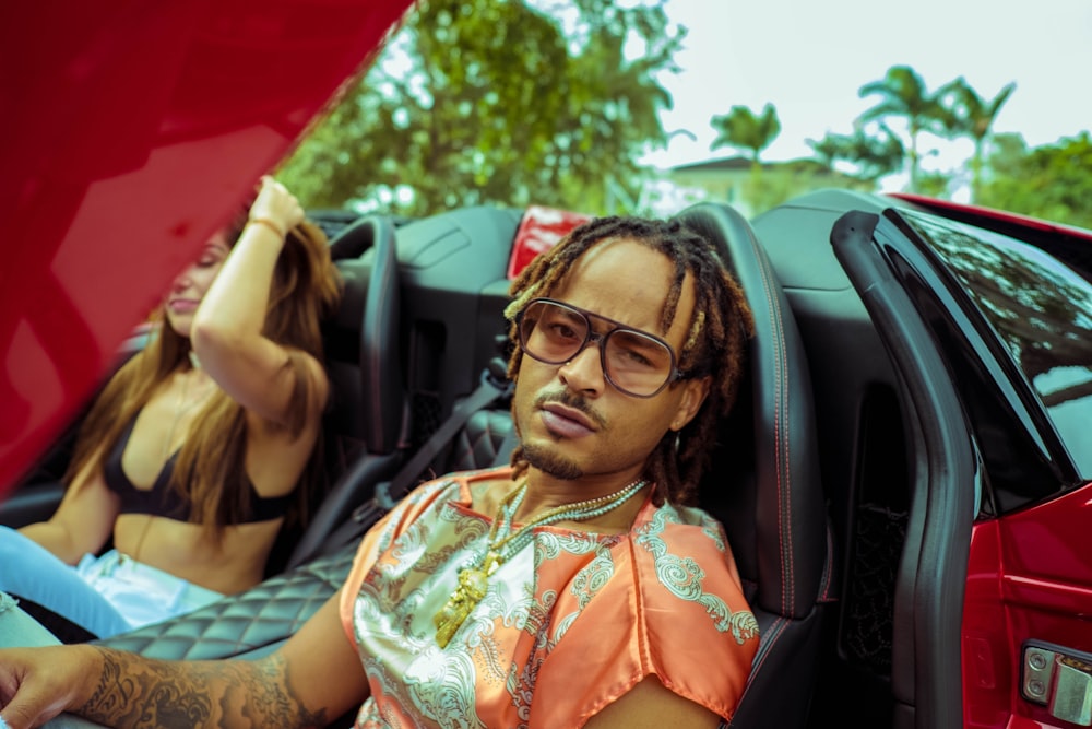 woman in orange and white floral dress wearing black sunglasses sitting inside car during daytime