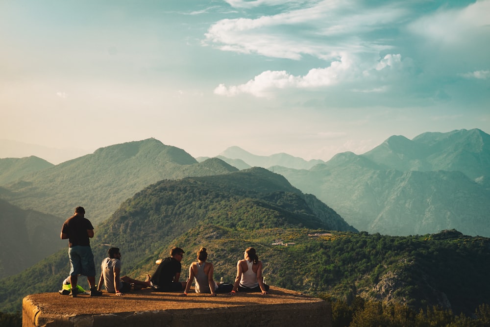 people sitting on brown rock near green mountains during daytime