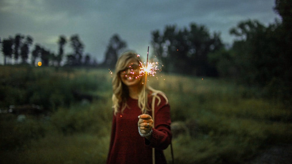 woman in red sweater holding sparkler