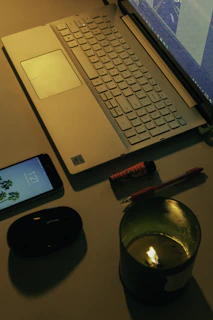 A warm, inviting desk with a notebook, pen, and a softly glowing candle beside a laptop.