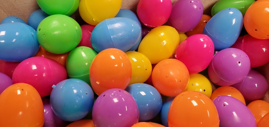 A collection of colorful plastic eggs in various shades including blue, green, pink, purple, orange, and yellow, spread out in a pile.
