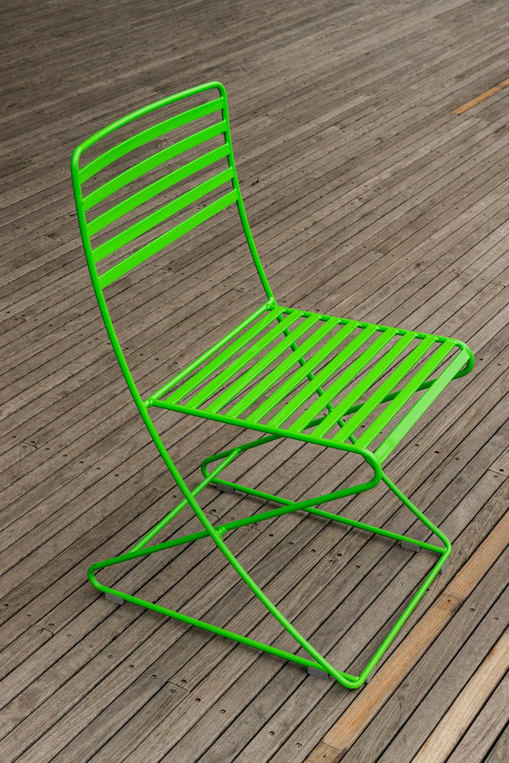 green metal chair on gray wooden floor