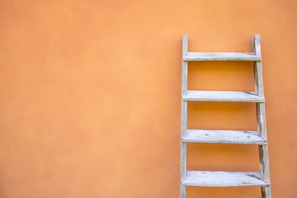 white wooden ladder leaning on orange wall