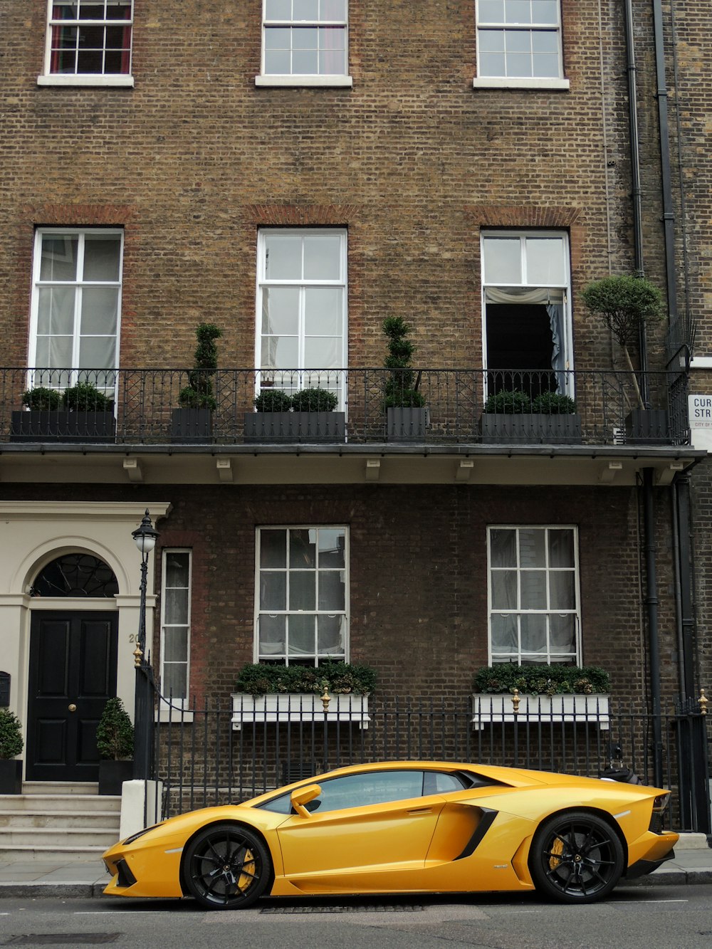 yellow porsche 911 parked in front of brown brick building