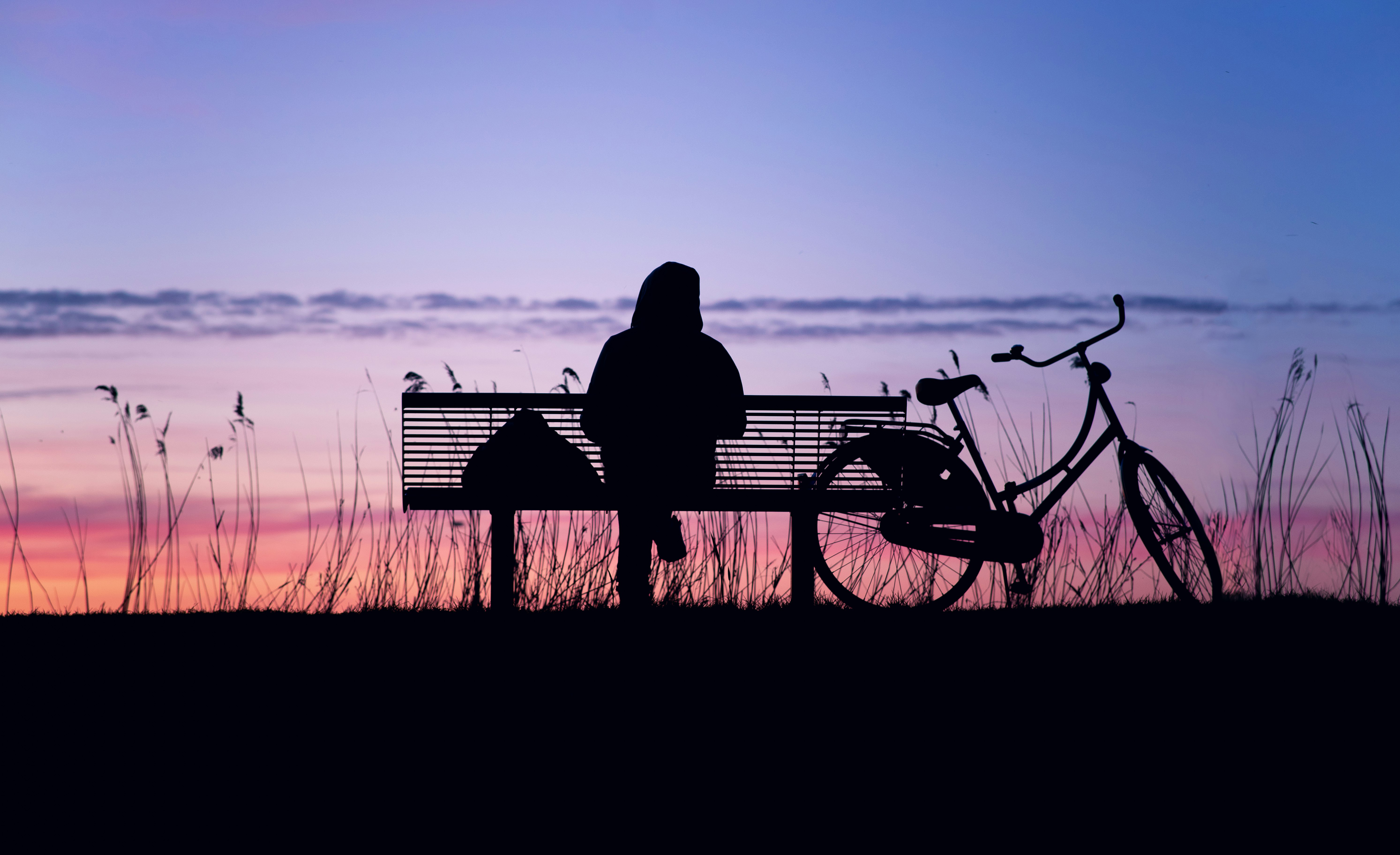 silhouette of person sitting on bench during sunset