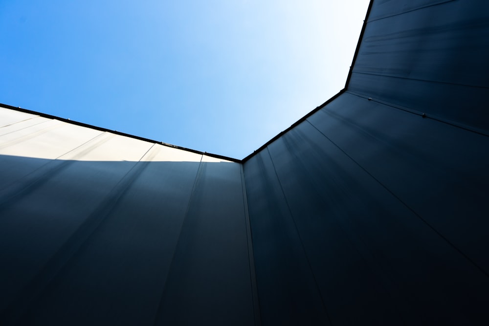 昼間の青空下の青いガラス張りの高層ビルのローアングル撮影