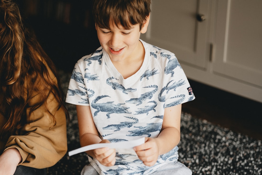 boy in white and blue floral button up t-shirt sitting on black and white textile