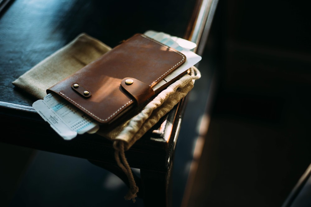 brown leather long wallet on brown wooden chair
