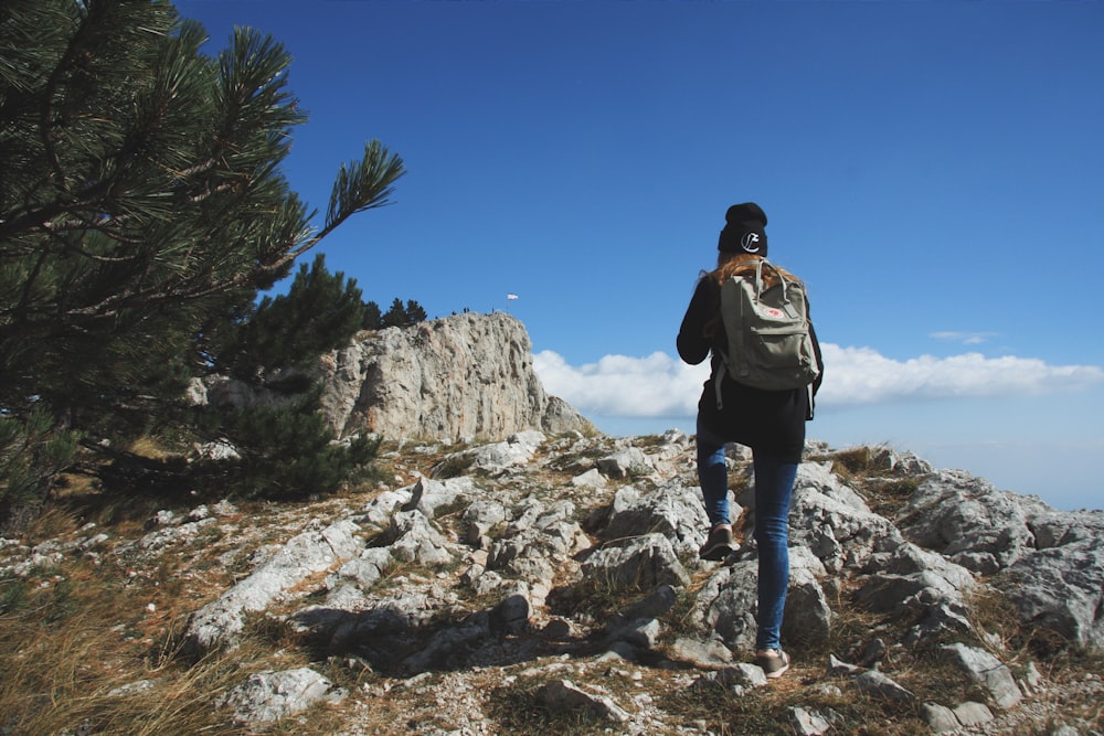 man in black jacket and black pants standing on rocky mountain during daytime