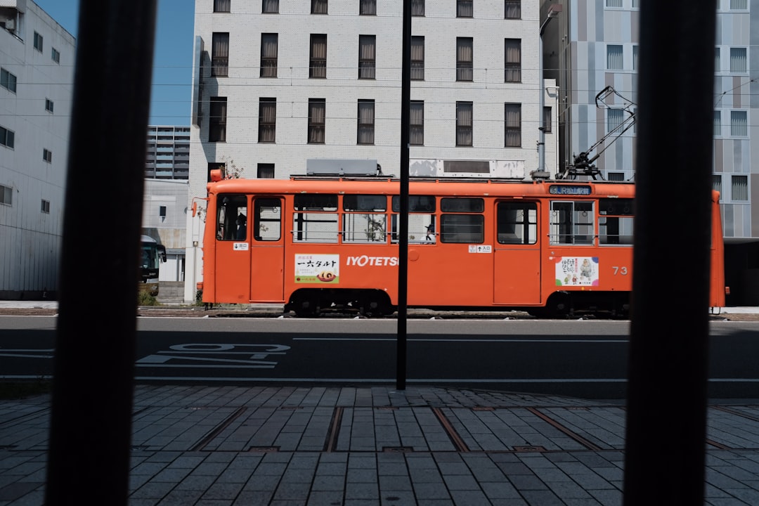 red bus on road near white concrete building during daytime