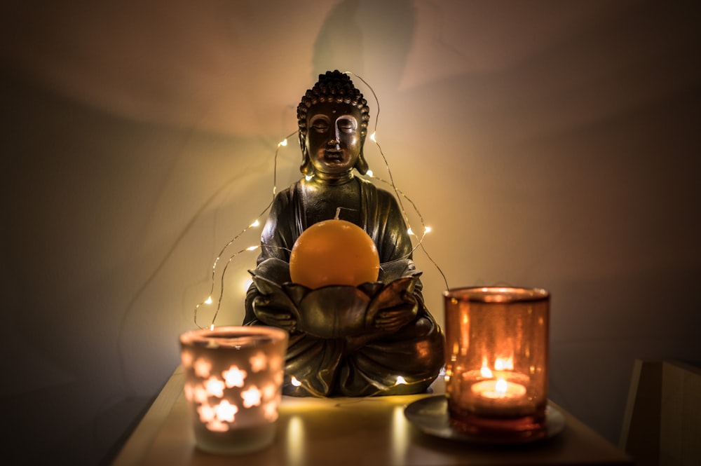 gold buddha figurine beside lighted candles