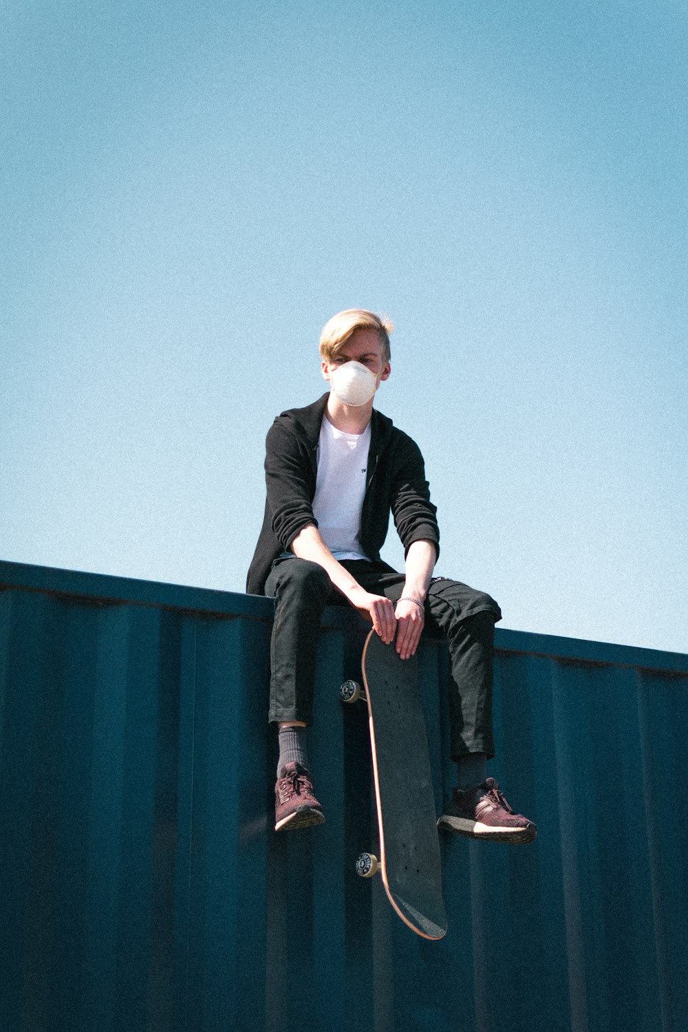 man in black long sleeve shirt and black pants sitting on black wooden bench