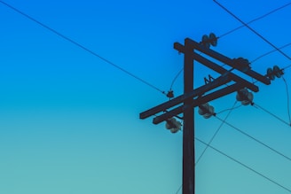 brown electric post under blue sky during daytime