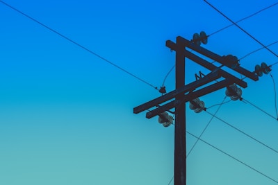 brown electric post under blue sky during daytime