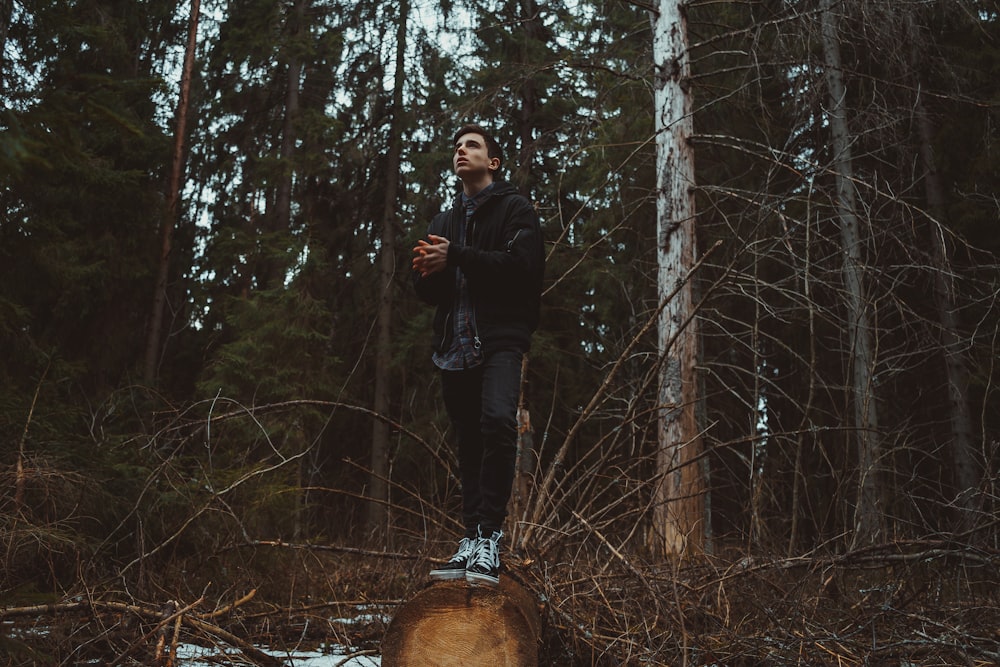 homme en veste noire debout sur la forêt pendant la journée