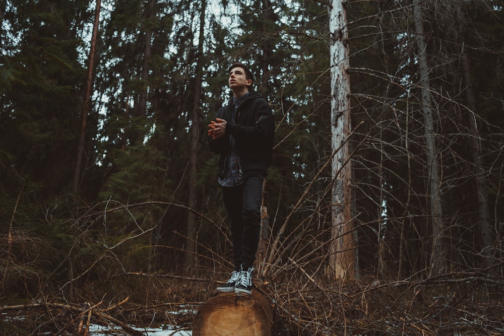 man in black jacket standing on forest during daytime