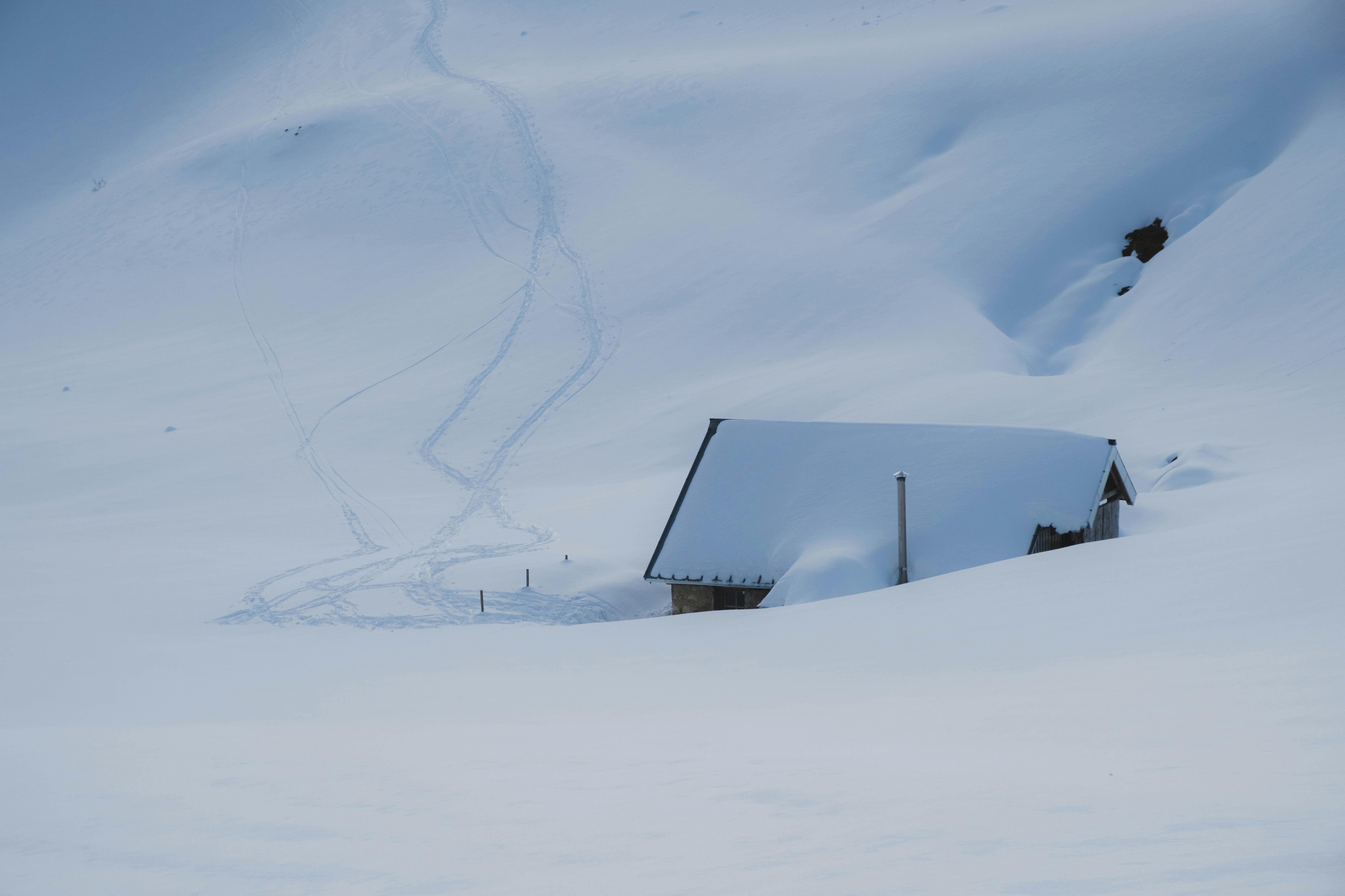 black house on snow covered ground under white clouds