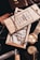 An arrangement of men's accessories including a wooden box labeled 'Bourbon Cedar' with a chain draped over it. Surrounding items include a gold wristwatch, a leather wallet, sunglasses, and a knife with a wooden handle. The composition suggests a theme of luxury and sophistication.
