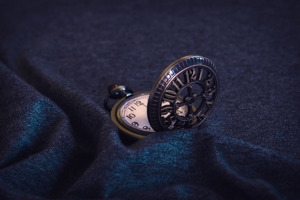 gold pocket watch on blue textile
