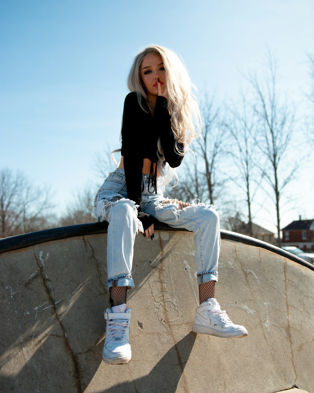 woman in black long sleeve shirt and blue denim jeans sitting on black metal railings during