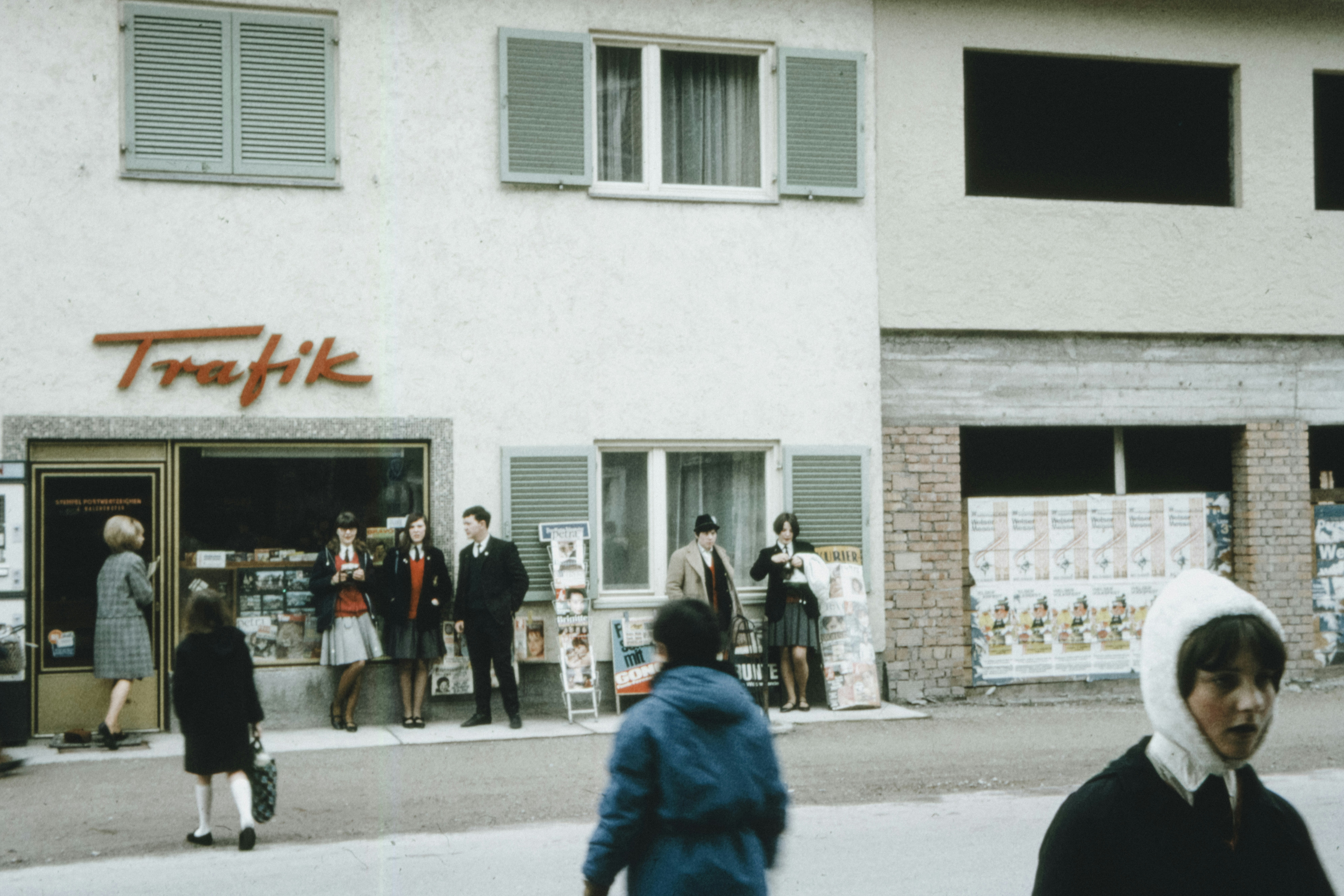 people walking on sidewalk near white concrete building during daytime