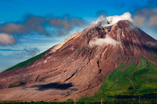 brown mountain under blue sky during daytime in Mount Sinabung Indonesia