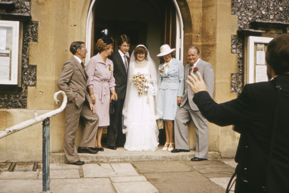 man in black suit jacket holding hands with woman in white wedding gown