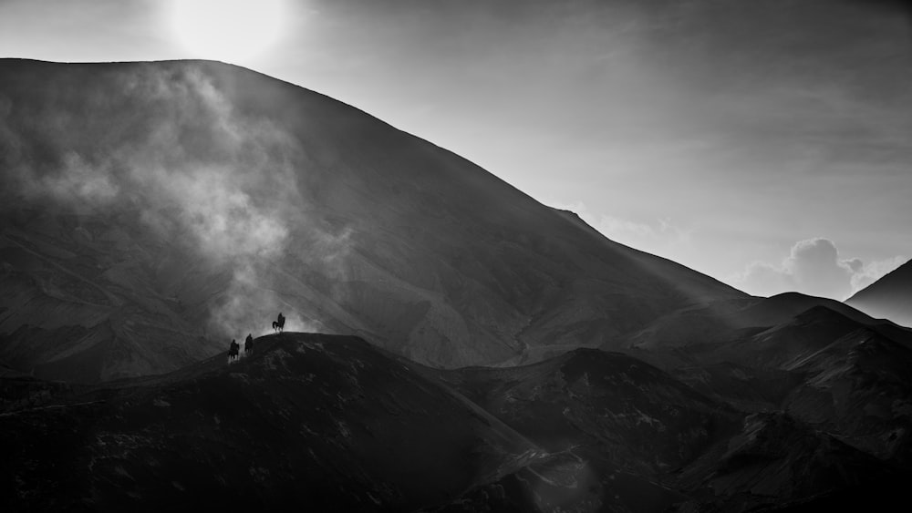 grayscale photo of person standing on top of mountain