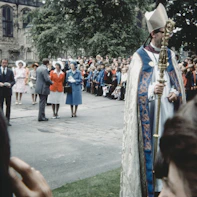 A large outdoor ceremony with crowd control and safety personnel in action.