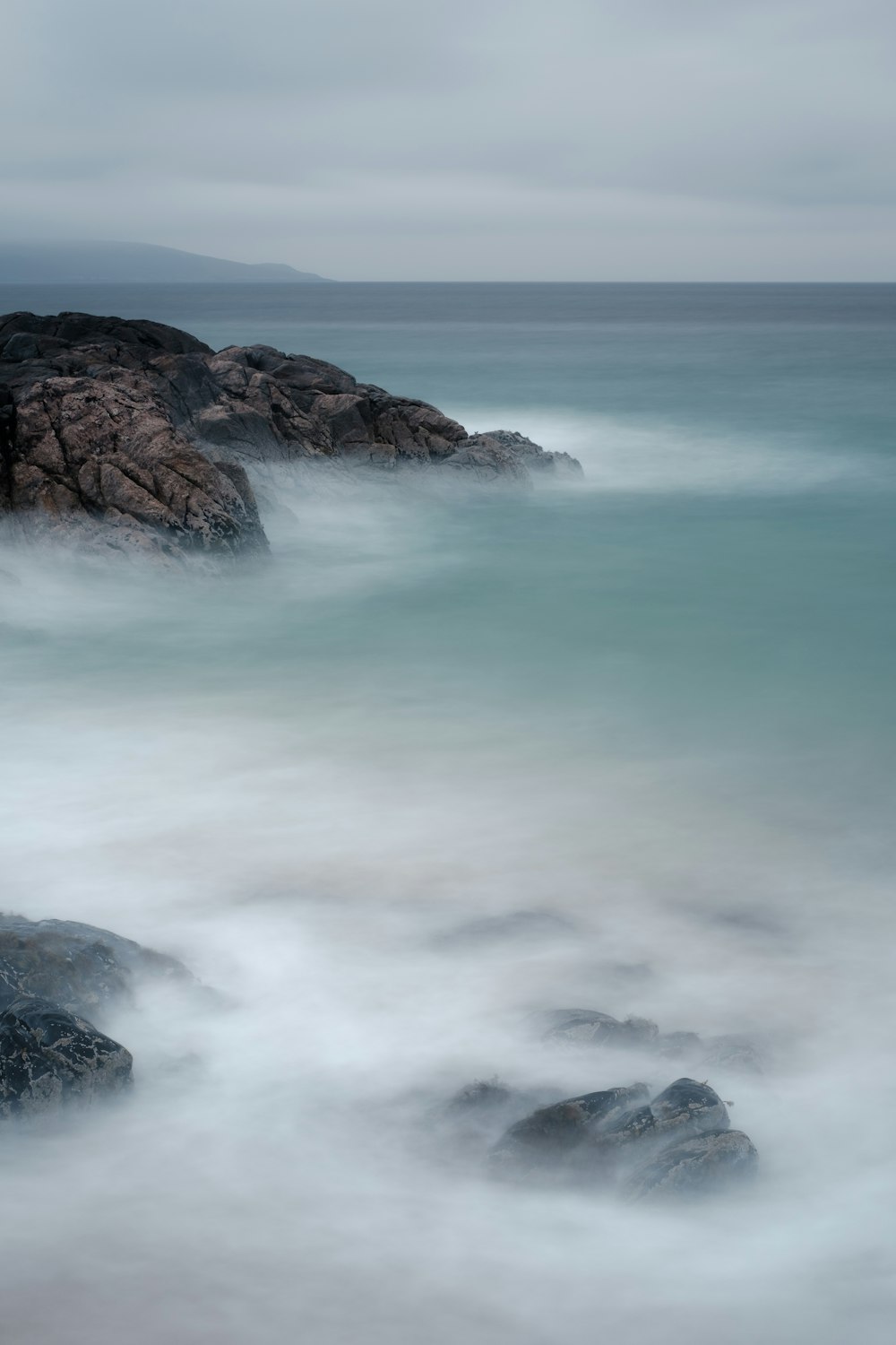 ondas do oceano batendo em formação rochosa marrom durante o dia