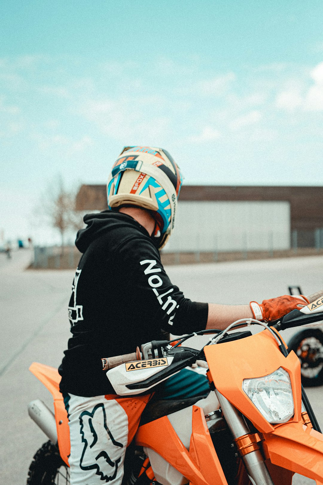 man in black and orange jacket riding orange motorcycle