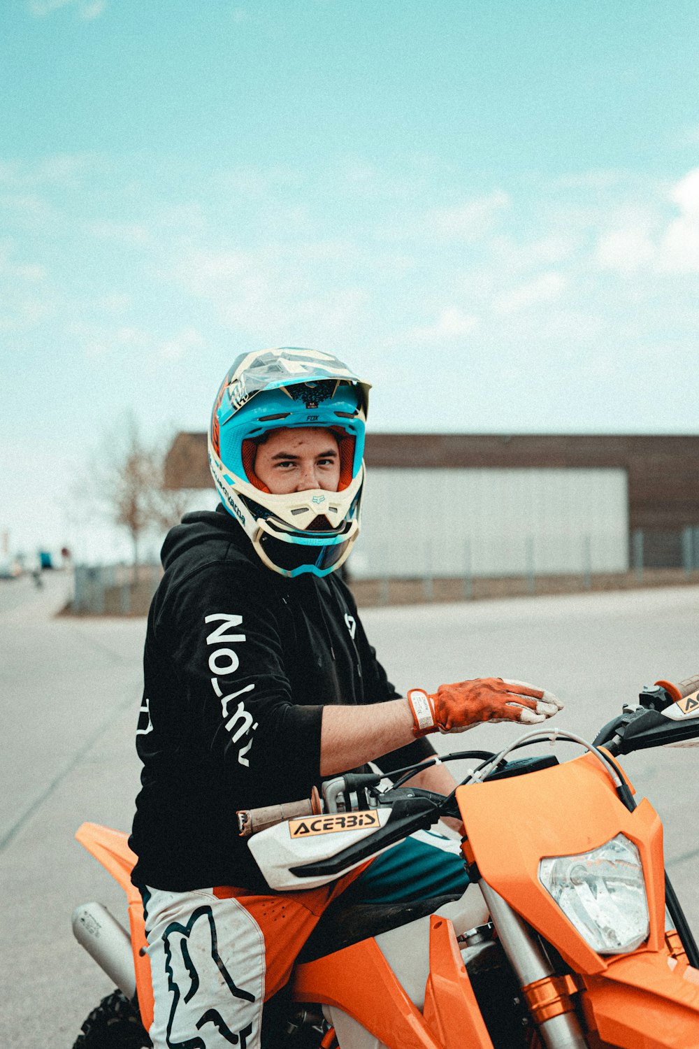 man in black and white jacket riding orange motorcycle