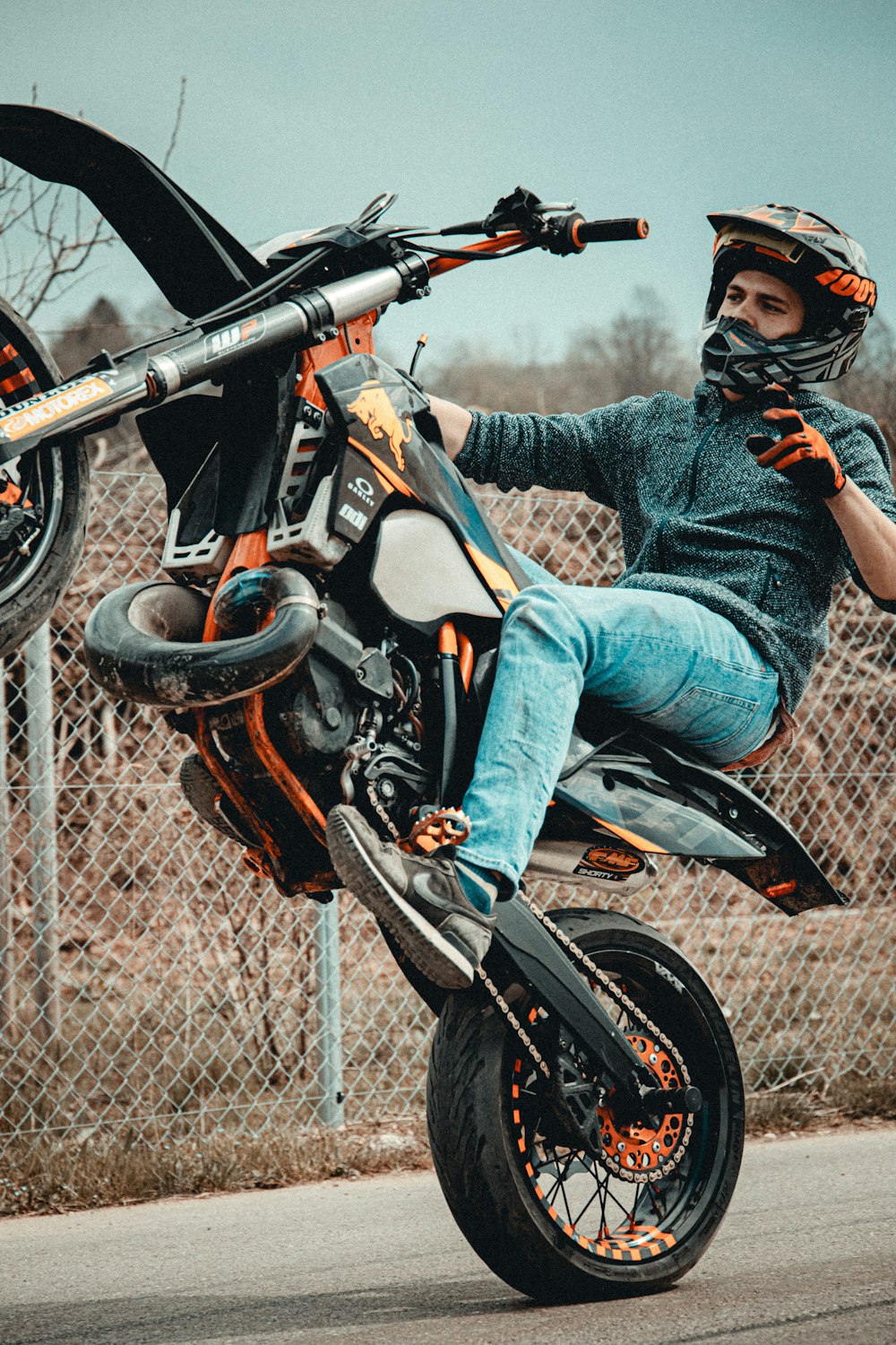 woman in blue denim jeans and black leather boots riding on black and orange motorcycle