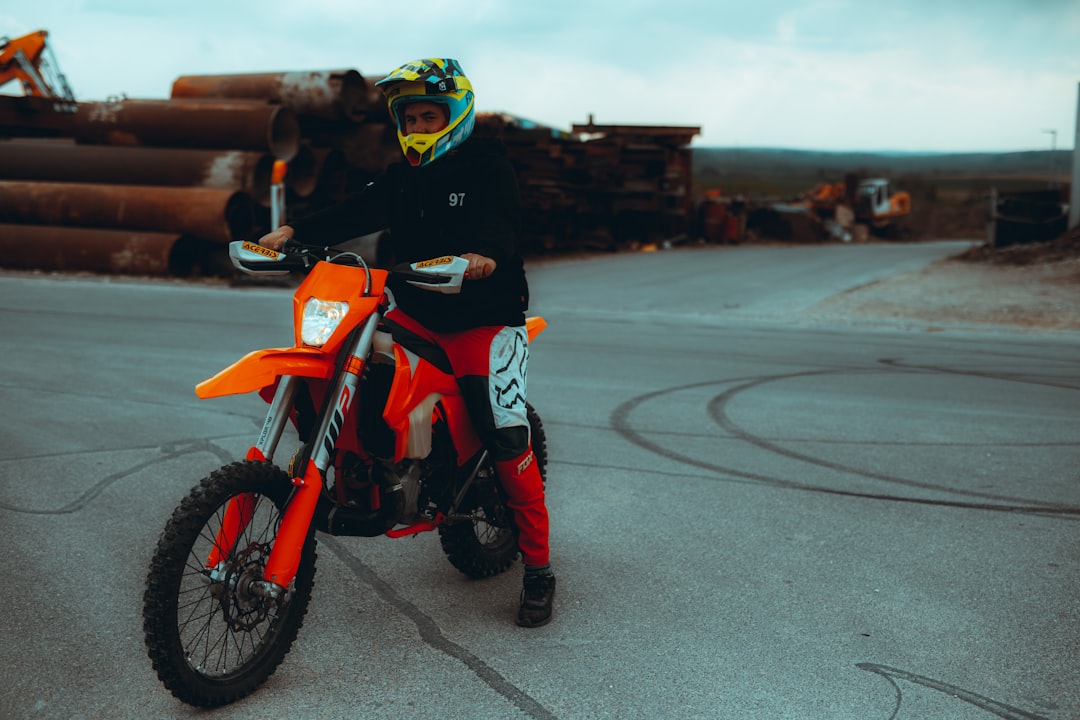 man in black helmet riding orange and black motorcycle during daytime