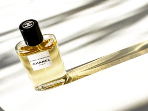 Monochrome image of a classic Chanel perfume bottle with a soft shadow on a clean white surface.