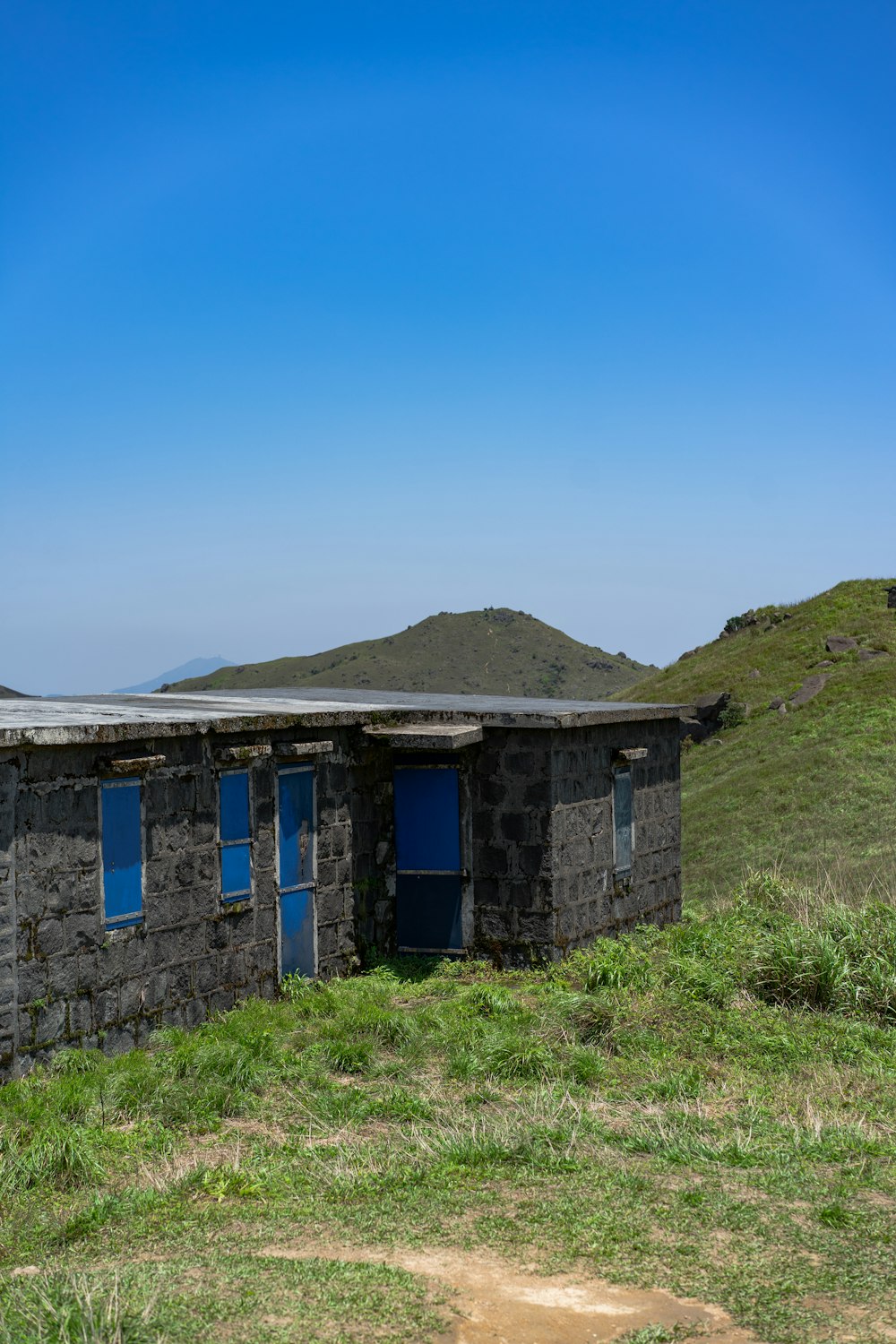 edifício de concreto azul e cinza perto do campo de grama verde sob o céu azul durante o dia