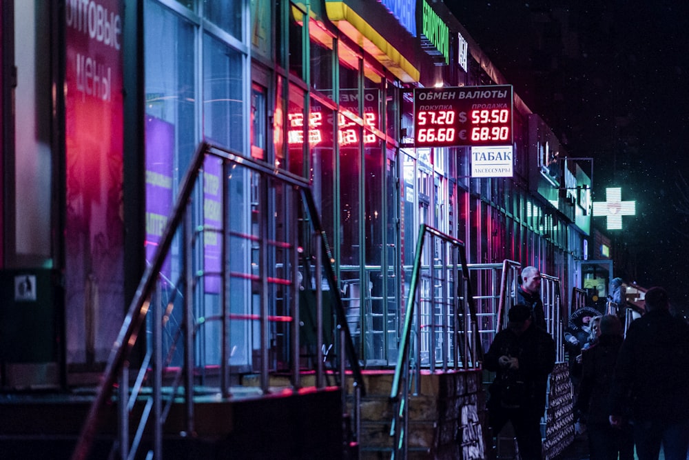 man in black jacket standing near red and yellow building during night time