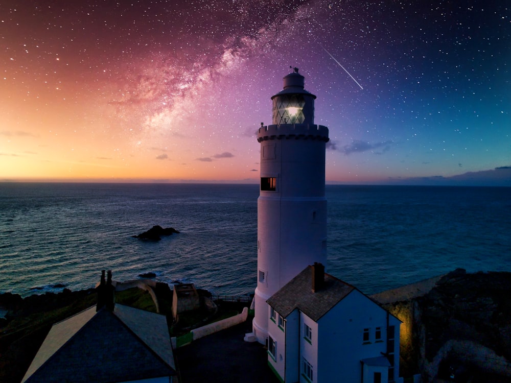 white and black lighthouse near body of water during night time