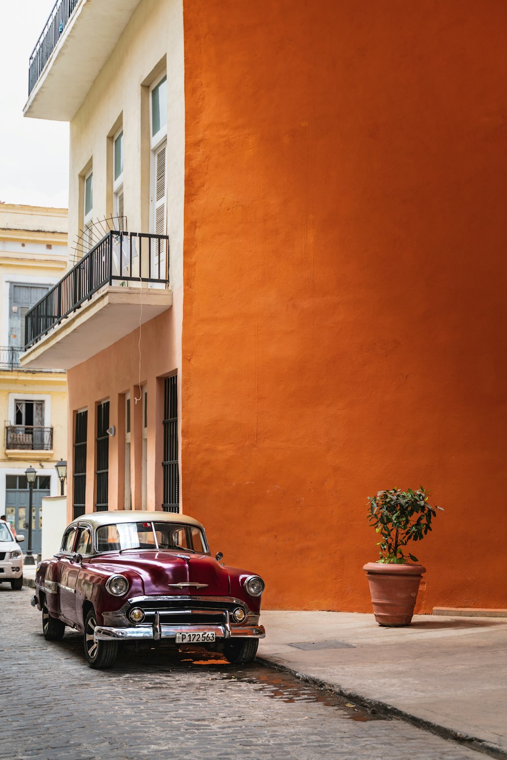 red car parked beside brown concrete building during daytime