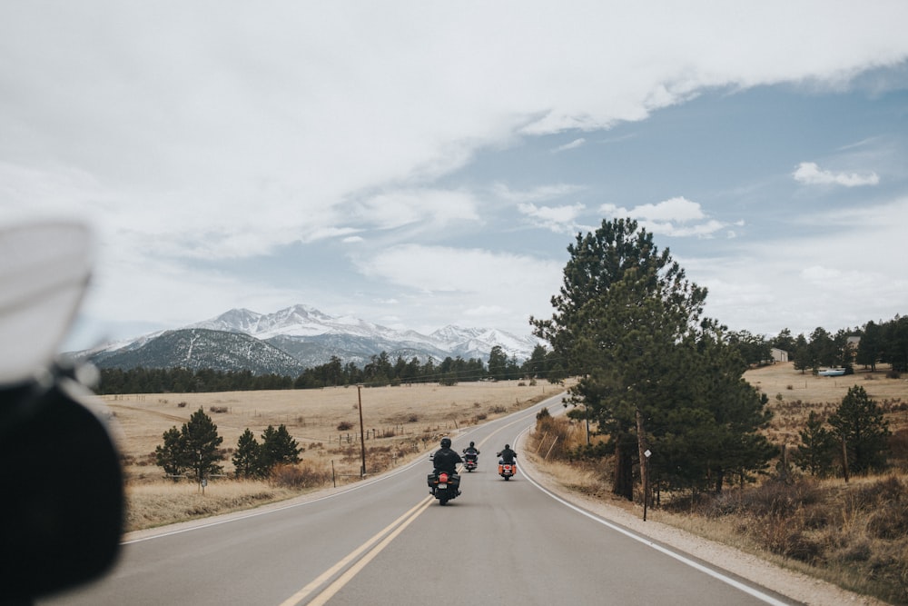 낮에는 푸른 나무와 산 근처 도로에 검은 오토바이