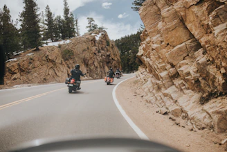 Motorcycle winding through scenic mountain roads under a clear blue sky.