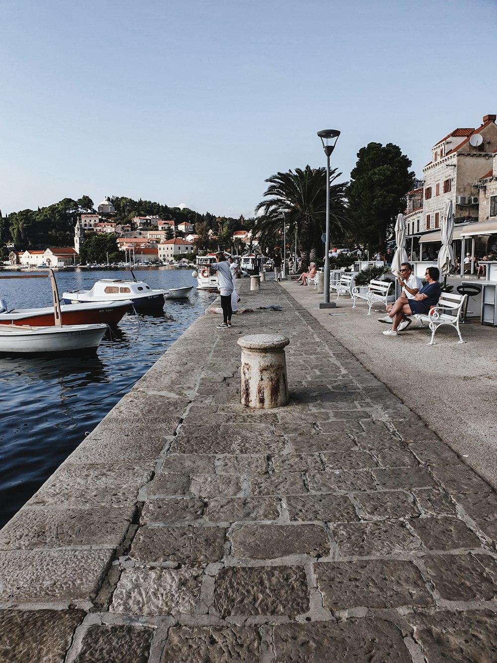 people sitting on bench near body of water during daytime